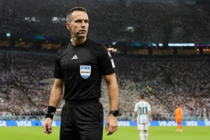 Arbitre de football en tenue noire sur un terrain de stade international lors d'un grand match FIFA