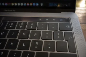 Gros plan sur la touche tiret d'un clavier Mac AZERTY avec mise en évidence du raccourci clavier