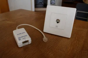 Prise téléphonique murale et filtre ADSL débranché posés sur une table, vérification d'une ligne téléphonique coupée